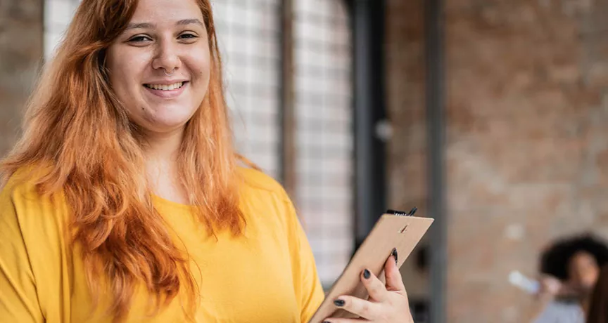 Jovem empresária sorri para a câmera segurando um tablet