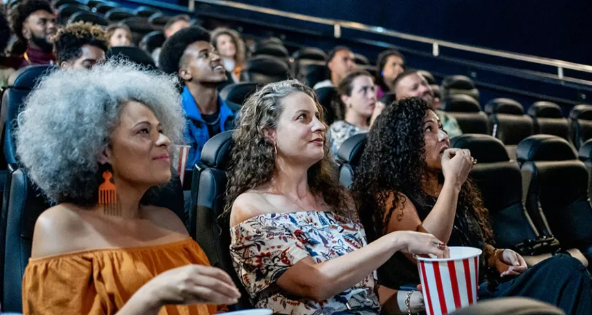Três amigas assistem um filme brasileiro no cinema