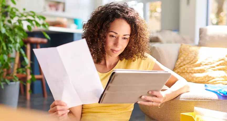 Mulher analisa documentos na sala da sua casa