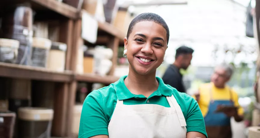 Foto mostra funcionária de uma loja de cerâmicas sorrindo para a câmera