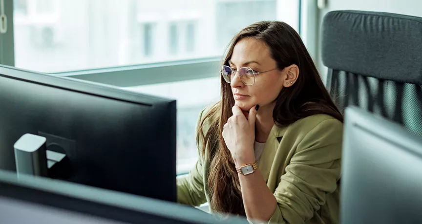 mulher olhando para computador pensativa.