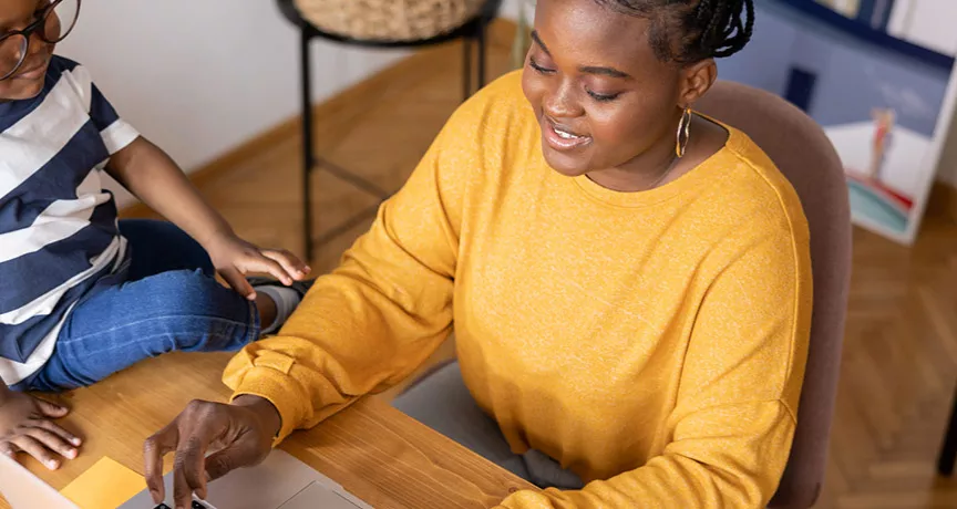 mulher trabalhando de home office com filho ao lado.