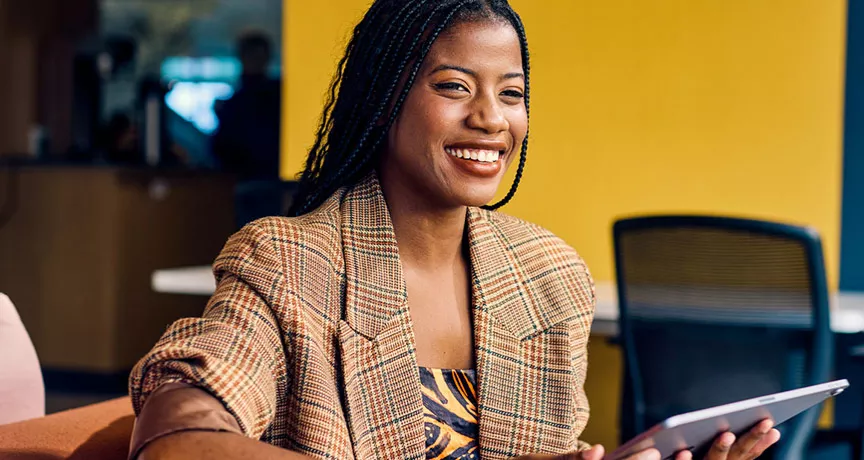 mulher sorrindo enquanto segura tablet.