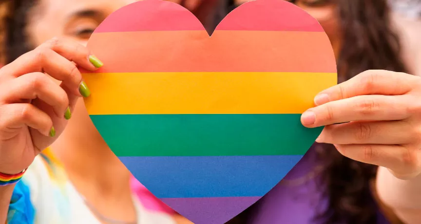 Foto mostra duas pessoas segurando um coração de arco-íris