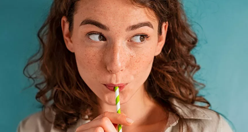 Foto mostra uma mulher tomando uma bebida de canudinho