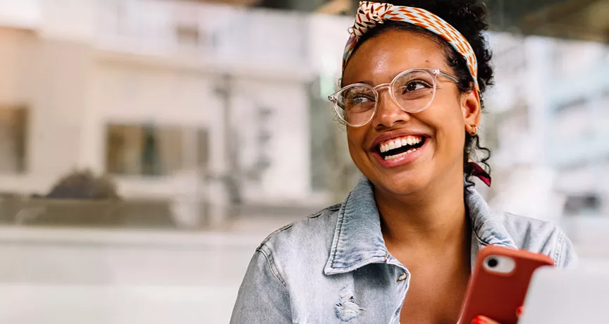 mulher sorrindo com celular na mão.
