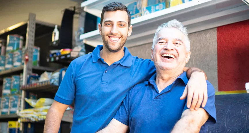 dois homens de diferentes idades sorrindo no trabalho.