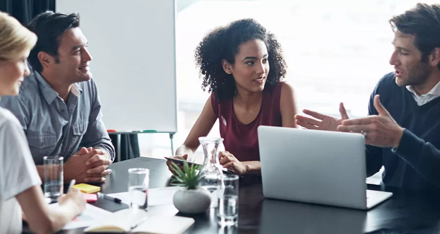 4 pessoas discutindo algo em mesa de reunião.