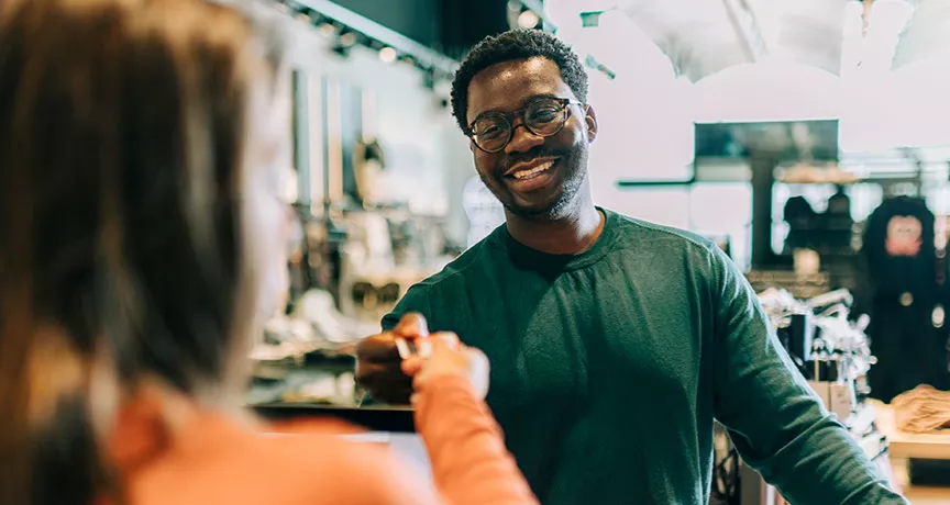 homem pagando compras enquanto sorri.