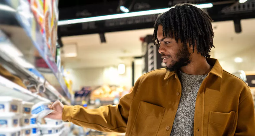 homem escolhendo itens de uma prateleira do supermercado.