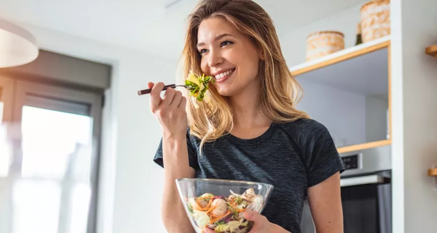 Imagem mostra uma mulher loira comendo salada