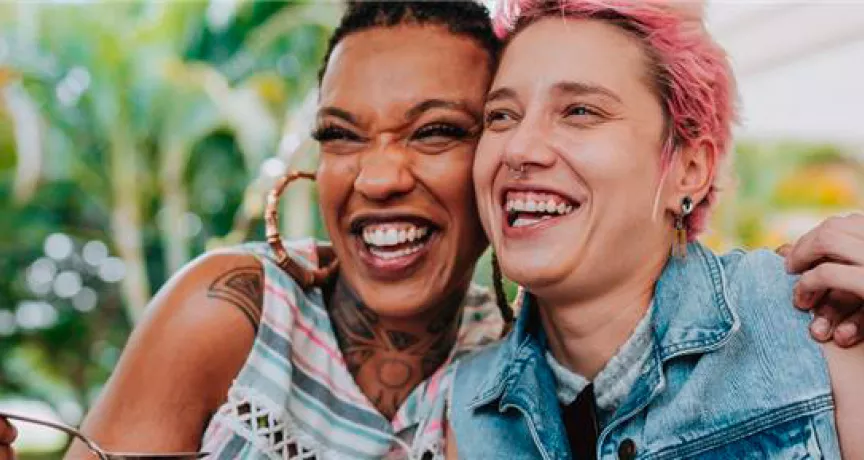 Imagem mostra duas mulheres abraçadas sorrindo e comendo felizes
