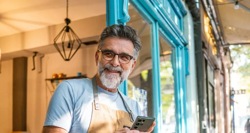 A imagem mostra um homem usando avental na frente de um estabelecimento