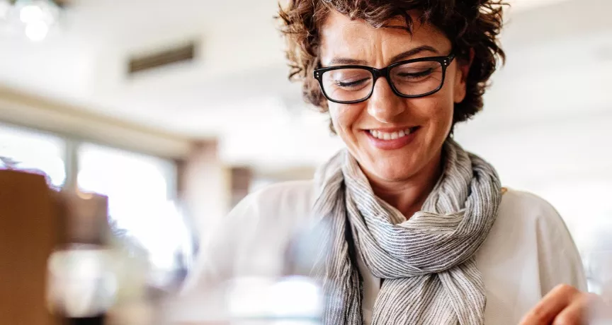 A imagem mostra uma mulher de óculos se alimentando em um restaurante