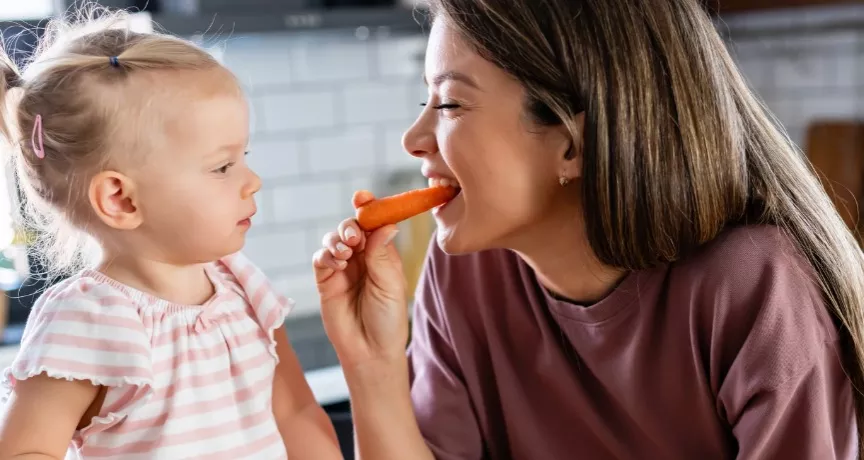 A imagem mostra uma mulher e uma criança comendo frutas