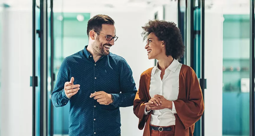 duas pessoas conversando em corredor de escritório.