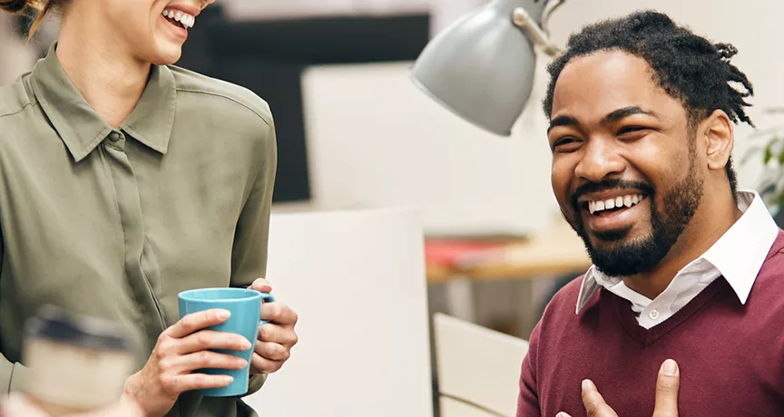 pessoas sorrindo e conversando em ambiente corporativo.