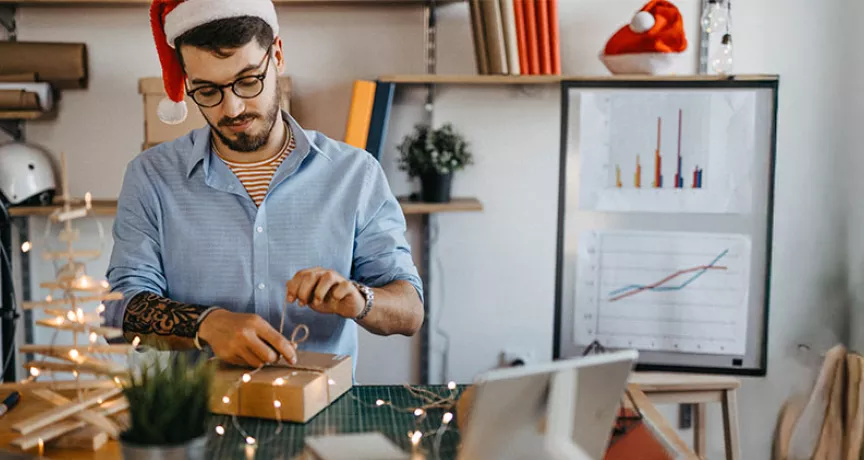 Funcionário em home office desembala um presente de Natal da empresa