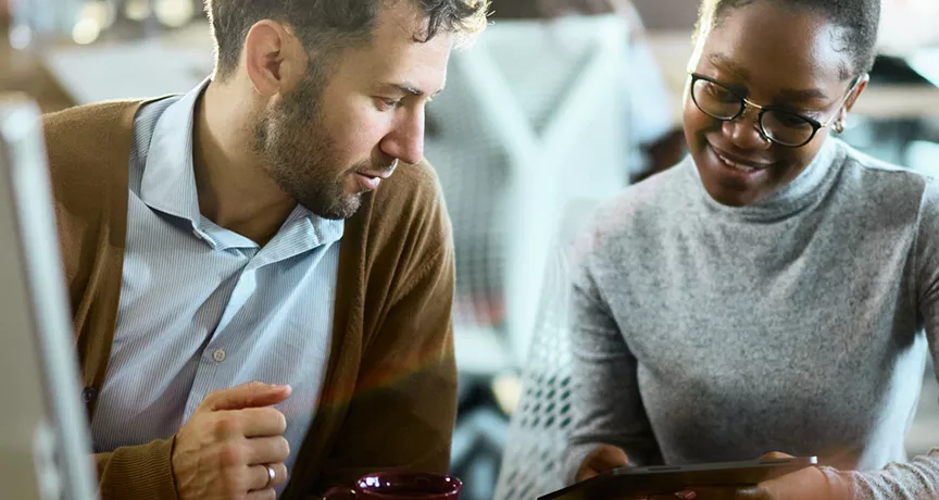 duas pessoas conversando enquanto olham algo em tablet.