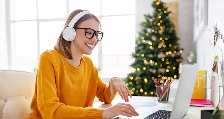Colaboradora trabalha em home office com árvore de Natal ao fundo