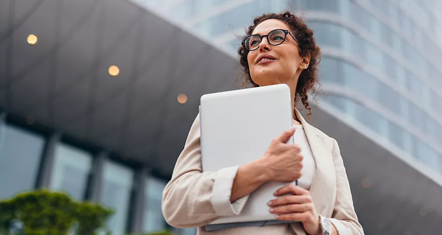 Foto mostra uma executiva em frente ao prédio em que trabalha