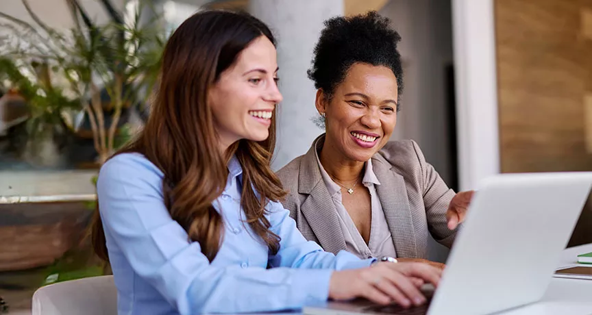 duas mulheres sorrindo para notebook.