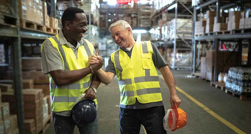 Foto mostra dois funcionários de uma empresa comemorando os resultados do final de ano