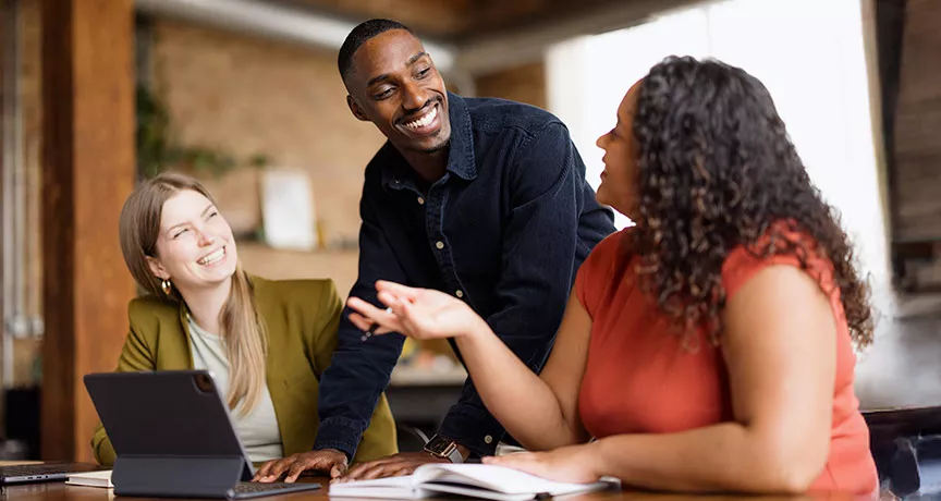 Três colegas de trabalho conversam animadamente durante uma reunião