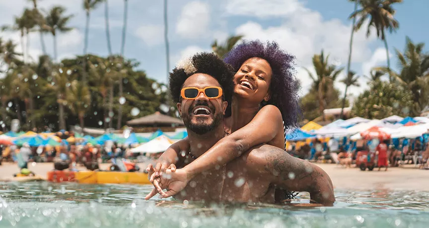 Foto mostra um casal curtindo férias na praia