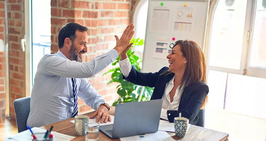duas pessoas fazendo "toca aqui" no trabalho.