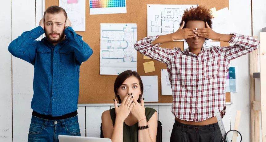 três pessoas imitando os “três macacos sábios”, da cultura japonesa.