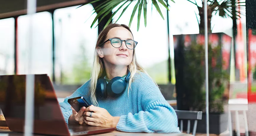 Foto mostra uma pessoa trabalhando em um notebook em uma sala ampla