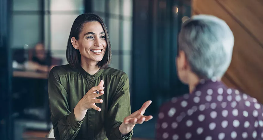 duas mulheres conversando em um ambiente corporativo 