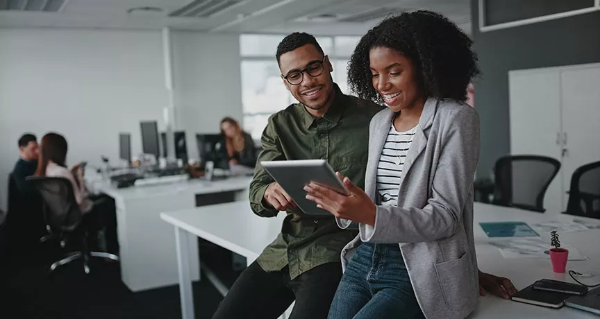 duas pessoas olhando informação em tablet no escritório.