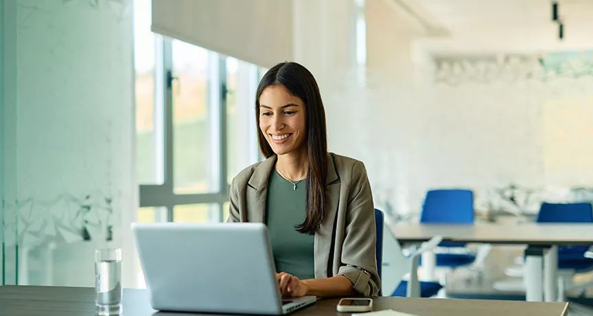 mulher sorrindo enquanto usa o computador no trabalho.