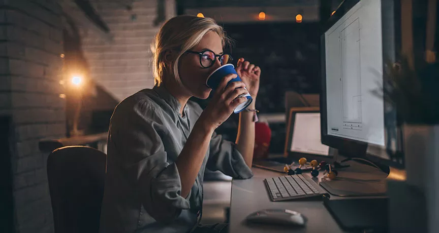 pessoa tomando chá enquanto trabalha à noite.