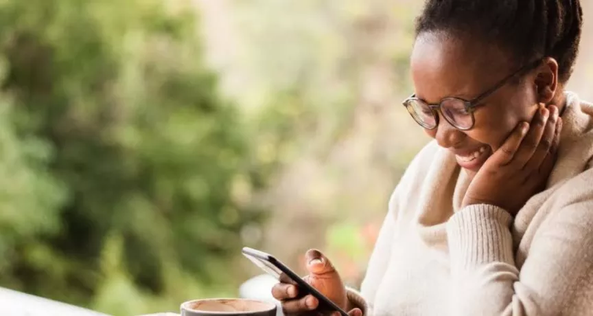 mulher negra sorrindo olhando para o celular