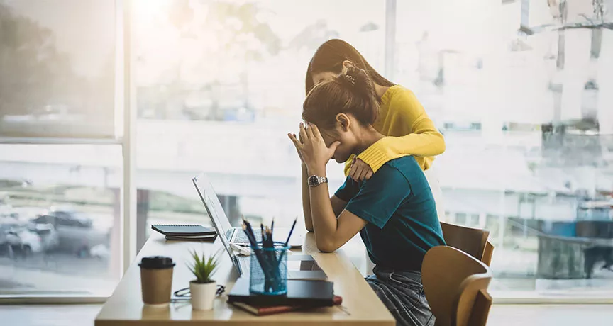 uma mulher oferecendo apoio para outra, que está preocupada com o trabalho.