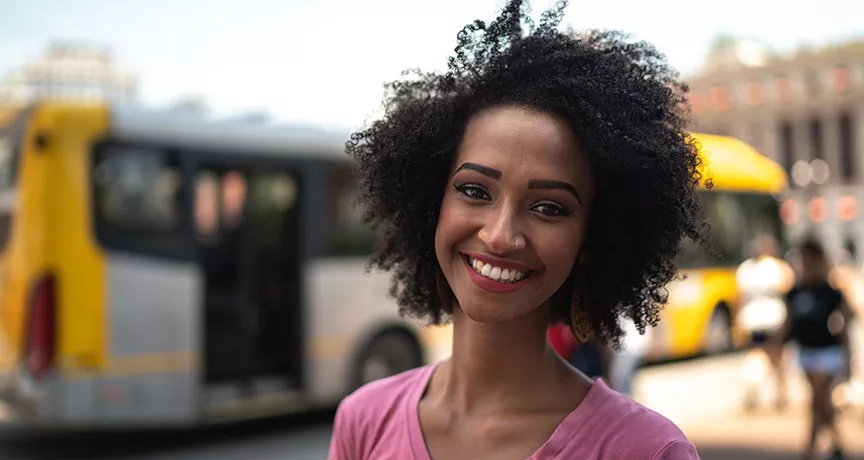 mulher sorrindo em frente a onibus.