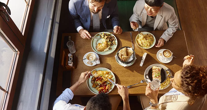 visão aérea time almoçando junto em mesa.