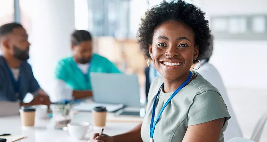 profissional da saúde sorrindo para a câmera rodeada por colegas.