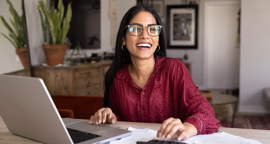 mulher sorrindo enquanto vê algo em notebook.