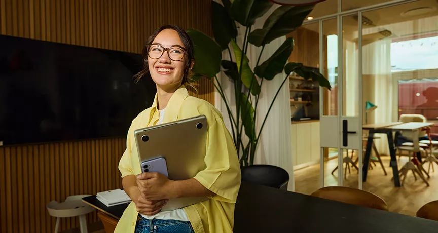 mulher sorrindo enquanto segura notebook.