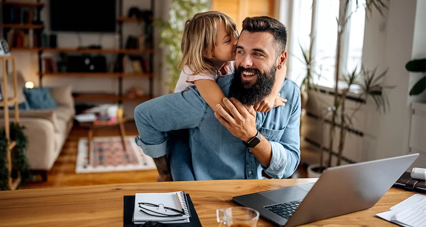 Foto de um homem brincando com sua filha durante um dia de home office