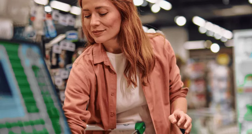 A imagem mostra uma mulher ruiva no mercado, fazendo compras