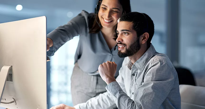 mulher mostrando algo a homem em tela de computador.