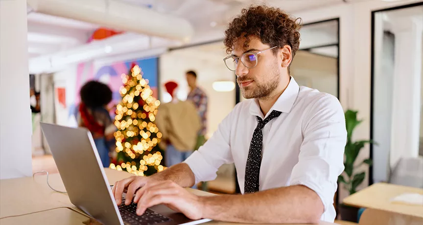 homem trabalhando com árvore de natal ao fundo.