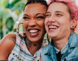 Imagem mostra duas mulheres abraçadas sorrindo e comendo felizes