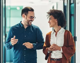 duas pessoas conversando em corredor de escritório.