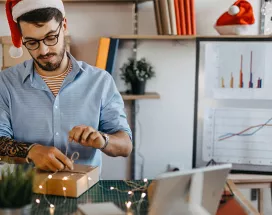 Funcionário em home office desembala um presente de Natal da empresa